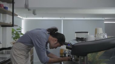 Kafe konsepti 4k Kararlılık. Asyalı erkek çalışan kahve makinesiyle kahve yapıyor..