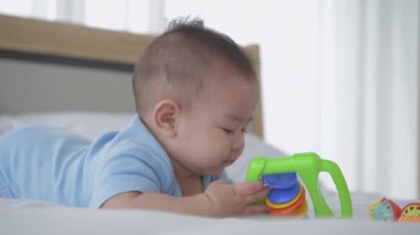 Aile kavramı 4k Kararlılığı. Bebek yatakta tek başına oyuncaklarla oynuyor..