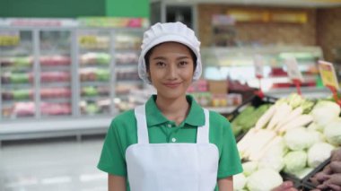 4k Kararlılığın alışveriş kavramları. Asyalı bir kadın mağazada kendine güvenerek sebze satıyor..