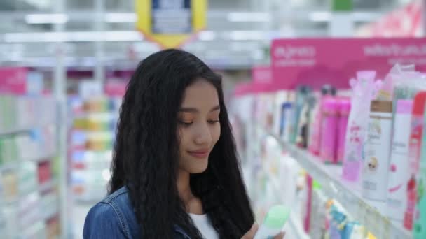 4K解像度のデパートの概念 アジアの女性はショッピングモールでシャワークリームを買っています — ストック動画