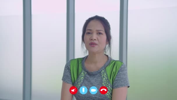 フィルムの接合部の後ろガラスに光をフィルターします 4K解像度のビデオ通話コンセプト アジアの女性選手はジムでの運動についてアドバイスをしています — ストック動画