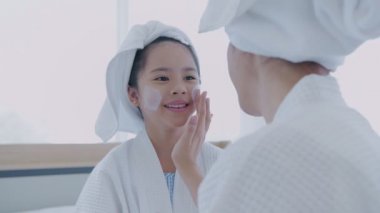 Spa konsepti 4k Çözünürlük. Annem yatak odasındaki kızına yüz maskesi takıyor..