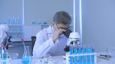 Araştırma konsepti 4K çözünürlüğü. Asyalı bilim adamları anomaliyi mikroskopla inceliyorlar..