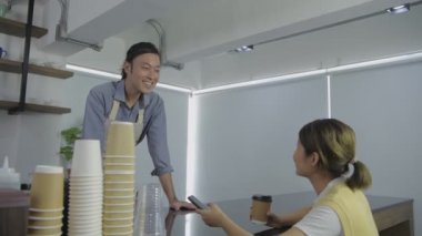 Barista 'nın 4k çözünürlük kavramı. Garson kahve dükkanında müşterilerle rahatça konuştu..