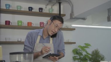 Barista 'nın 4k çözünürlük kavramı. Bir çalışan, içki siparişi vermek için arayan bir müşterinin telefonuna cevap veriyor..