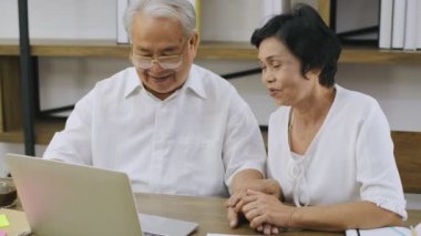 Aile kavramı 4k Kararlılığı. Ev bilgisayarlarında çalışan yaşlı bir çift..