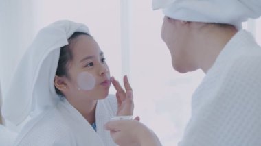 Spa konsepti 4k Çözünürlük. Annem yatak odasındaki kızına yüz maskesi takıyor..