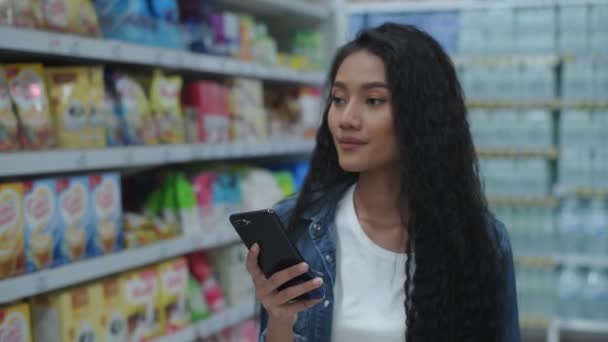 购买4K解像度的概念 年轻女性使用手机在商场里搜寻商品 — 图库视频影像