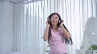 Tatil konsepti 4k Çözünürlük. Asyalı kızlar evde mutlu bir şekilde müzik dinleyip dans ediyorlar..