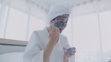 Spa konsepti 4k Çözünürlük. Asyalı kadın yatak odasında yüz kremi sürüyor..