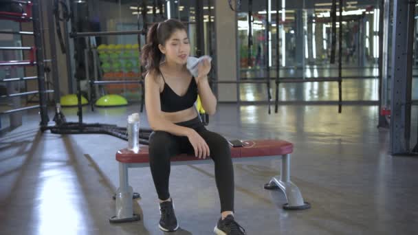 4K解像度的健康概念 一位年轻女子在体育馆里休息喝水 — 图库视频影像