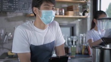 Barista 'nın 4k çözünürlük kavramı. Çalışanlar kahve dükkanında tabletleri olan müşterilerden emir alıyorlar..