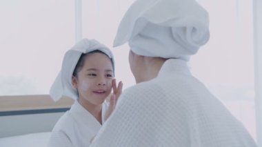 Spa konsepti 4k Çözünürlük. Annem yatak odasındaki kızına yüz maskesi takıyor..