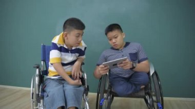 Eğitim konsepti 4k Kararlılık. Engelli çocuklar tabletle oyun oynuyorlar..