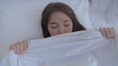 Tatil konsepti 4k Çözünürlük. Asyalı bir kadın sabah yatakta uyanır..