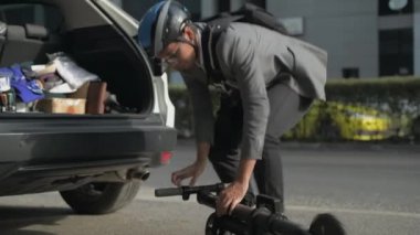 Enerji tasarruflu seyahat aracı konsepti 4k Çözünürlük. Asyalı bir adam arabasında scooter tutuyor..