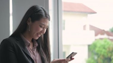 4k Kararlılığın iş konsepti. Asyalı kızlar ofisteki telefonu seve seve kullanıyorlar..