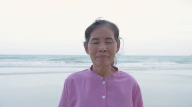Seyahat konsepti 4k Çözünürlük. Sahile bakan Asyalı yaşlı kadın..