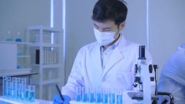 Araştırma konsepti 4K çözünürlüğü. Asyalı bilim adamları anomaliyi mikroskopla inceliyorlar..