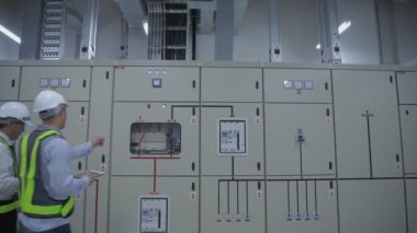 4k Kararlılığın iş konsepti. Mühendisler fabrikadaki elektrik ekipmanlarını incelemek için yürüyorlar..