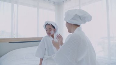Spa konsepti 4k Çözünürlük. Annem yatak odasındaki kızına yüz maskesi takıyor..