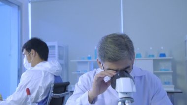 Araştırma konsepti 4K çözünürlüğü. Asyalı bilim adamları anomaliyi mikroskopla inceliyorlar..