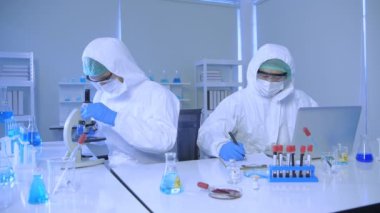 Araştırma konsepti 4K çözünürlüğü. Bilim adamları laboratuarda çalışmak için koruyucu giysiler giyerler..