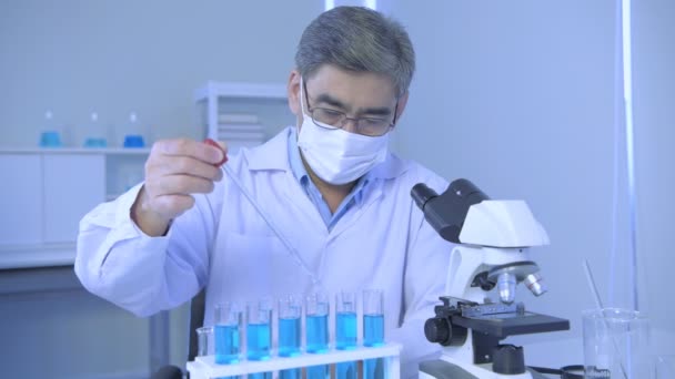 4K分解能の研究コンセプト 試験管に液体を滴下するアジアの男 — ストック動画