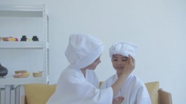 Spa konsepti 4k Çözünürlük. Asyalı anne ve kızı birbirlerine losyon sürüyorlar..