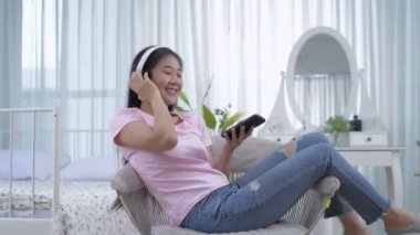 Tatil konsepti 4k Çözünürlük. Asyalı kızlar yatak odasında müzik dinlemekten zevk alıyorlar..