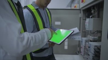 Mühendislik konsepti 4k Çözünürlük. Operatör, yeşil ekran tabletindeki bilgilere dayanarak işi gözden geçiriyor.