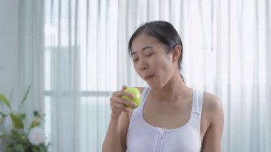 Sağlık konsepti 4k Çözünürlük. Asyalı kız evde yeşil elma yiyor..