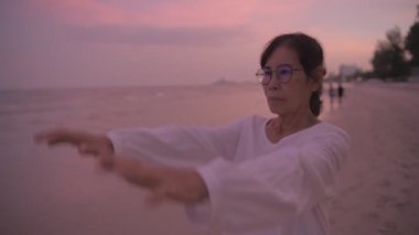 Seyahat konsepti 4k Çözünürlük. Asyalı yaşlı bir kadın kumsalda mutlu bir şekilde nefes alıyor..