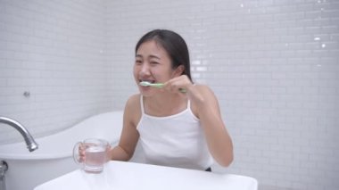 Günlük 4k çözünürlük konsepti. Banyoda diş fırçalayan Asyalı kadın..