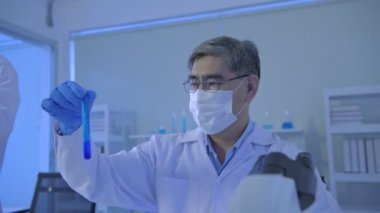 Araştırma konsepti 4K çözünürlüğü. Asyalı bilim adamları laboratuvar çözümlerini karşılaştırıyorlar.