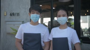 Kafe konsepti 4k Kararlılık. Asyalı erkek ve kadın çiftler müşteri hizmetleri için dükkan açmak için bir tabela alıyorlar..