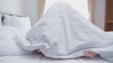 Tatil konsepti 4k Çözünürlük. Asyalı bir kadın gülümseyerek battaniyeden fırlıyor..