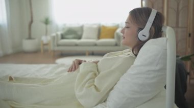 Hamile kadın konsepti 4k Kararlılık. Asyalı bir kız evde karnına bakıyor..