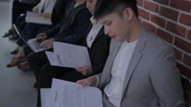 4k Kararlılığın iş konsepti. Ofis işi görüşmesini beklerken bir grup insan belgeleri inceliyor.