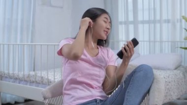 Tatil konsepti 4k Çözünürlük. Asyalı kızlar yatak odasında müzik dinliyorlar..