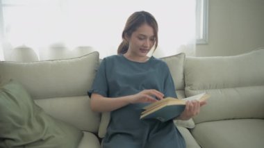 Hamile kadın konsepti 4k Kararlılık. Oturma odasında kitap okuyan bir kadın..