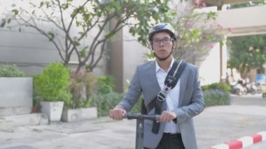 Enerji tasarruflu seyahat aracı konsepti 4k Çözünürlük. Yol kenarında scooter süren Asyalı bir adam..