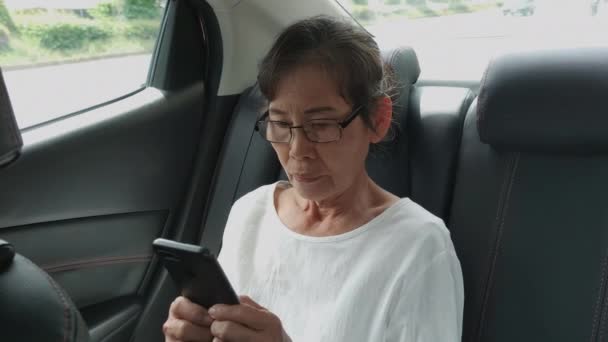 4K解像度の旅行の概念 車の中で携帯電話を再生するアジアの高齢女性 — ストック動画