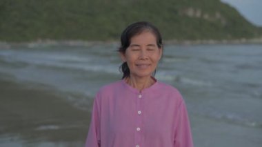 Seyahat konsepti 4k Çözünürlük. Sahile bakan Asyalı yaşlı kadın..