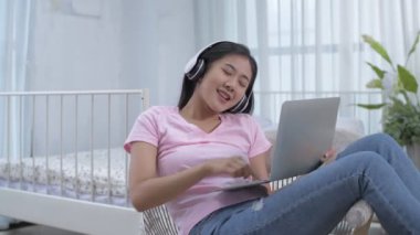 Tatil konsepti 4k Çözünürlük. Yatak odasında bilgisayar oynayan Asyalı genç kadın..