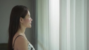 Tatil konsepti 4k Çözünürlük. Asyalı kızlar sabahları pencereden manzaraya bakarlar..