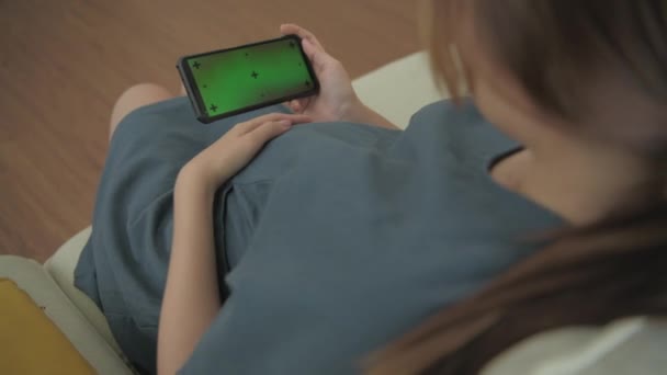 孕妇4K解析度的概念 一个女人在家里沙发上用智能手机 — 图库视频影像