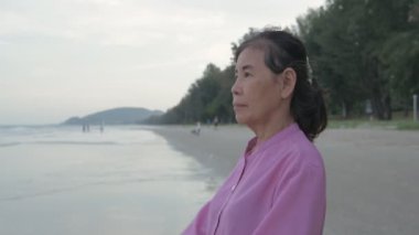 Seyahat konsepti 4k Çözünürlük. Asyalı yaşlı bir kadın kumsalda mutlu bir şekilde nefes alıyor..