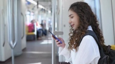 4k Kararlılığın Turizm konsepti. Elektrikli trenle seyahat eden güzel bir kız telefonda oynuyor..