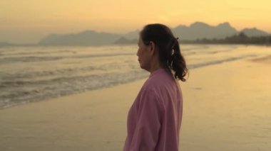 Seyahat konsepti 4k Çözünürlük. Asyalı yaşlı bir kadın kumsalda mutlu bir şekilde nefes alıyor..